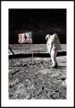 Fotografia astronauty stojącego na powierzchni księżyca przy fladze Stanów Zjednoczonych. Plakat z białym marignesem dookoła.