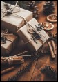 Plakat na Boże Narodzenie z prezentami w otoczeniu gałązek świerku, lasek cynamonu i suszonych plastrów pomarańczy. Fotografia wprowadza do pomieszczenia świąteczny klimat