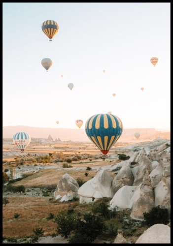 Plakat ze zdjęciem unoszących się balonów na gorące powietrze na tle wulkanicznych skał w Turcji