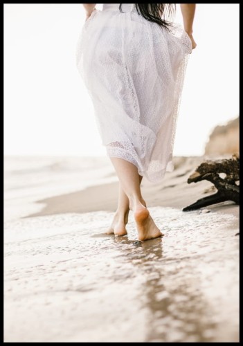 Zdjęcie kobiety spacerującej po plaży nad brzegiem morza