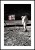 Fotografia astronauty stojącego na powierzchni księżyca przy fladze Stanów Zjednoczonych. Plakat z białym marignesem dookoła.